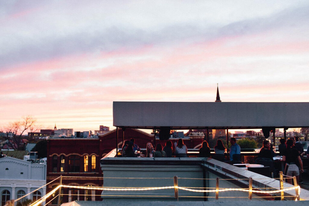 Patrons sitting at tables at an outdoor rooftop bar