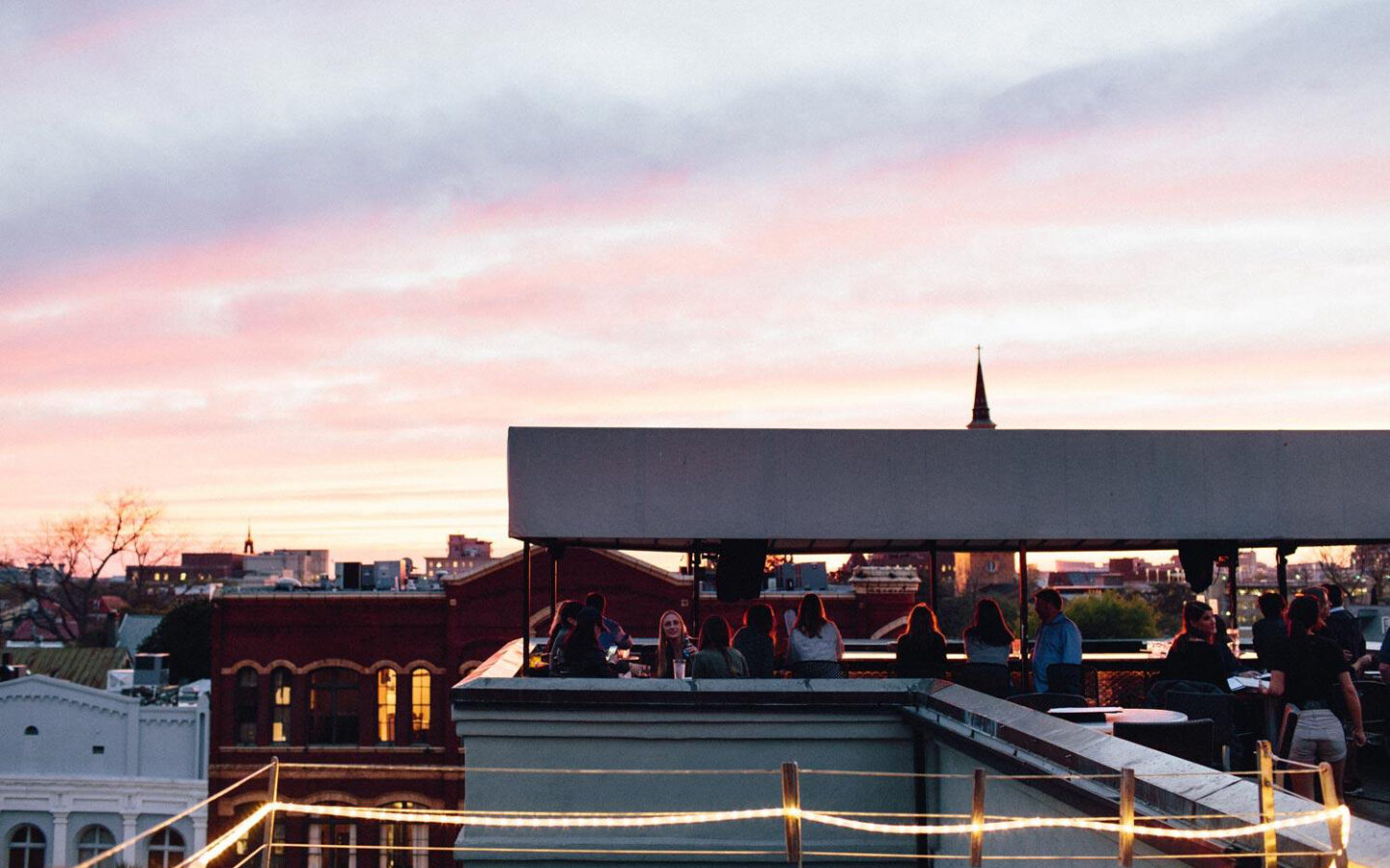 Patrons sitting at tables at an outdoor rooftop bar
