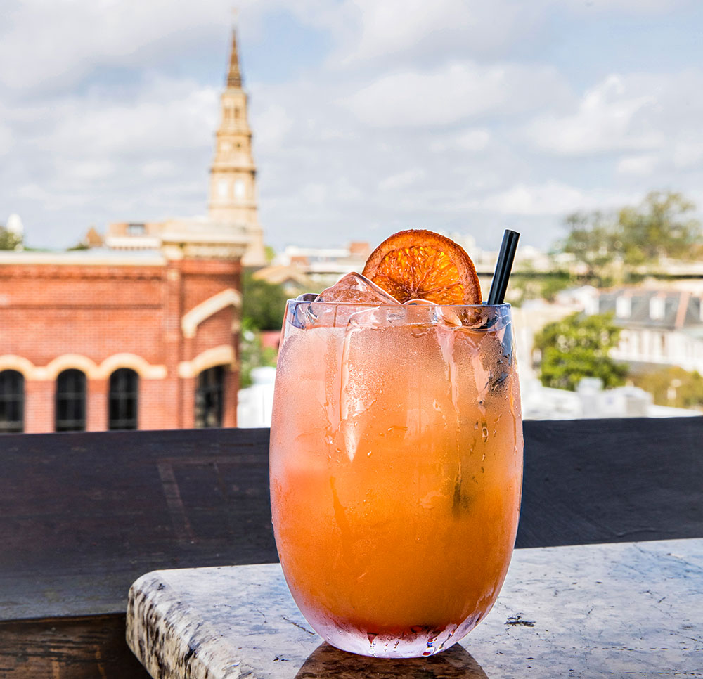 Orange cocktail filled with ice, garnish, and a straw