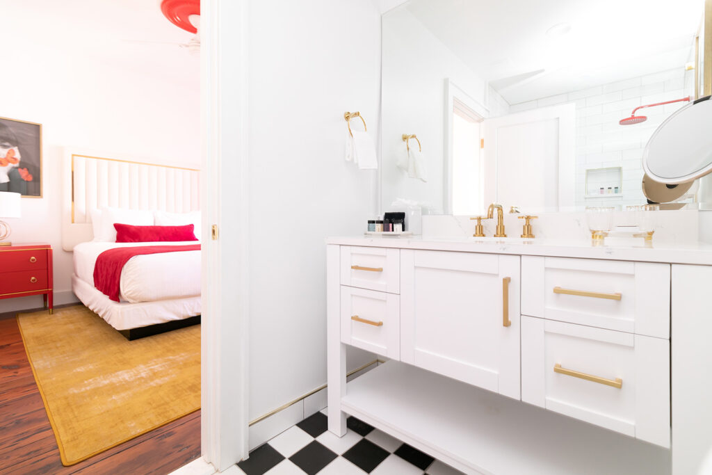 Hotel room bathroom with checkerboard tile and sink with gold accents