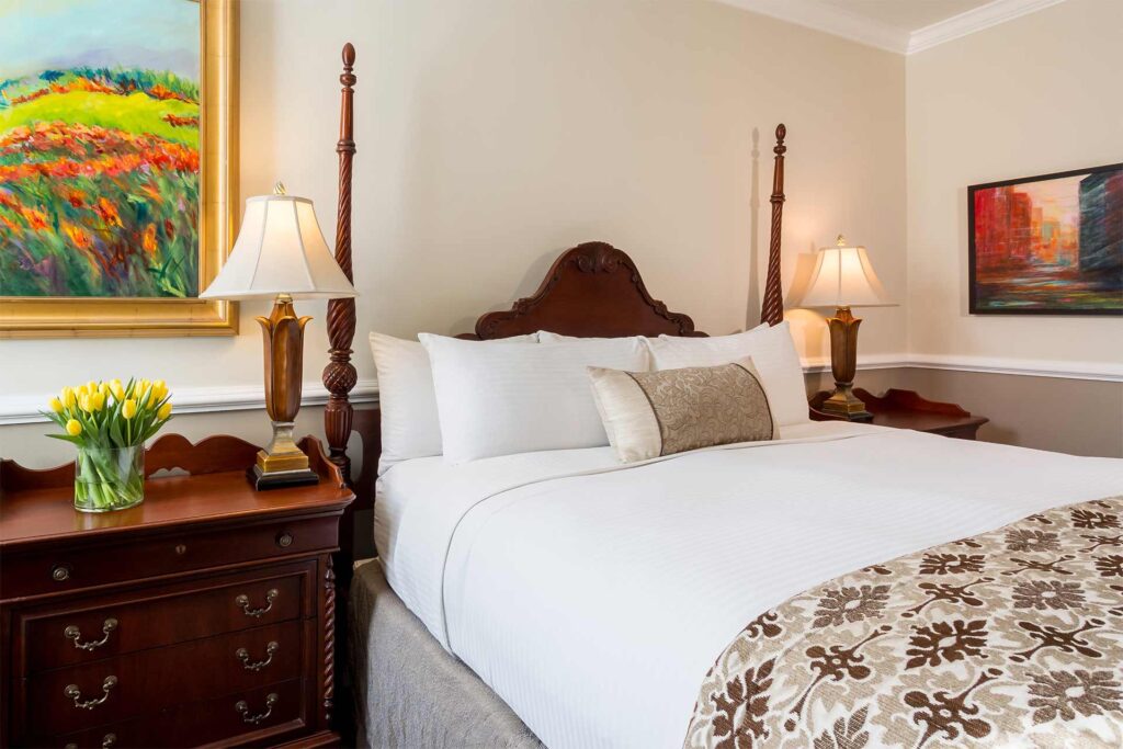 King bed with paintings and flowers to the side
