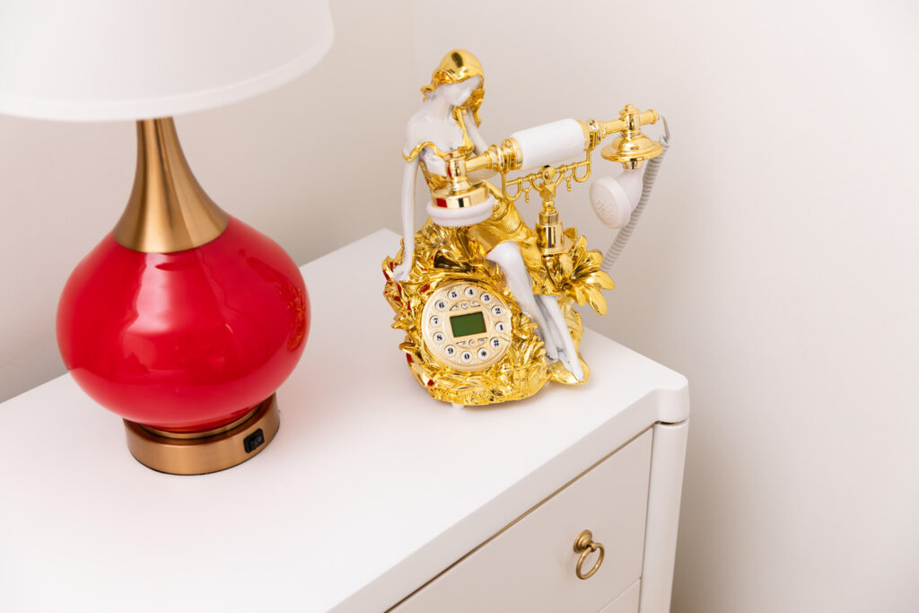 Gold phone next to a red lamp on a bedside table